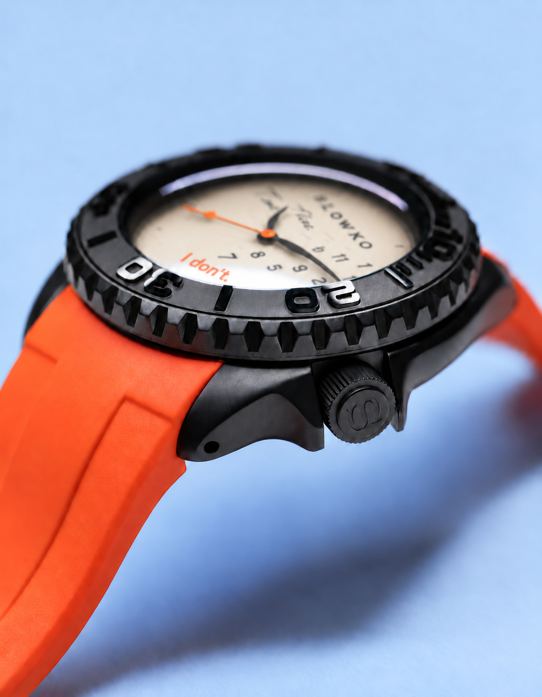 Angled close-up of the SLOWKO black case, bezel, crown and orange strap.